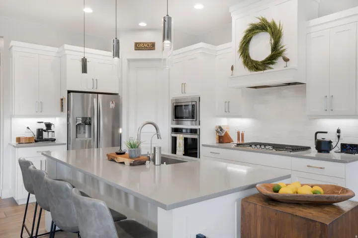 Kitchen featuring white shaker cabinetry, stainless steel appliances, a large center island with a built-in sink, pendant lighting, and a subway tile backsplash