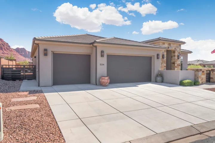 Contemporary stucco exterior with stone accents, a dual garage, and a concrete driveway