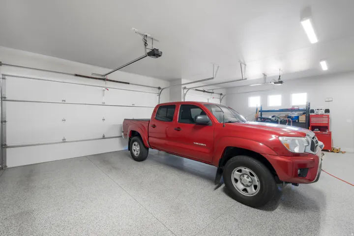 Garage featuring a speckled epoxy floor, multiple overhead light fixtures, and high-set windows providing ambient illumination