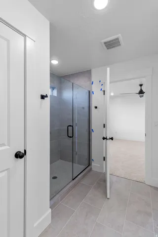 Walk-in shower with clear glass enclosure, gray subway tile, and a pebble-finish shower pan