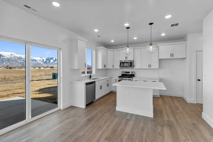 Open-concept kitchen with white shaker cabinetry, stainless steel appliances, a center island, and wood-finish flooring