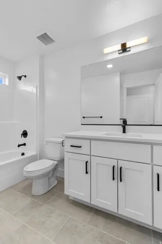 White shaker-style vanity with a light-colored countertop, undermount sink, and matte black faucet
