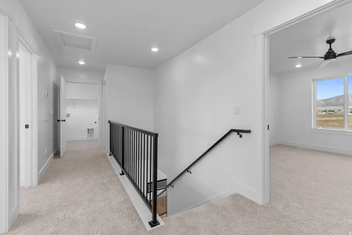 Light-colored carpeting throughout, recessed lighting, and modern black iron stair railing