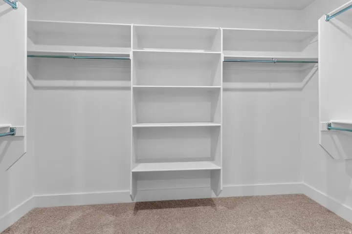 Built-in closet system featuring multiple shelves, hanging rods, and carpet flooring
