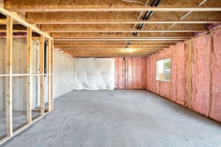 Unfinished basement with exposed ceiling joists, concrete flooring, wood framing, and wall insulation