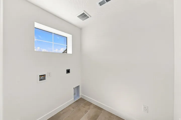 Utility area with a window, tile flooring, and white walls