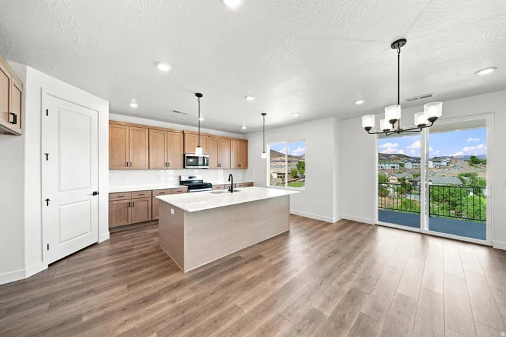 Kitchen featuring wood cabinetry, an island with a light-toned countertop, and recessed lighting