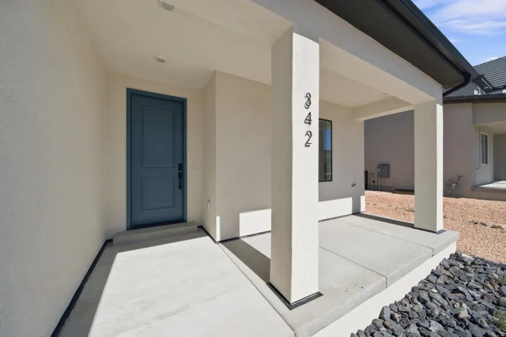 Covered front entry with a panel door, recessed lighting, and modern house numbers