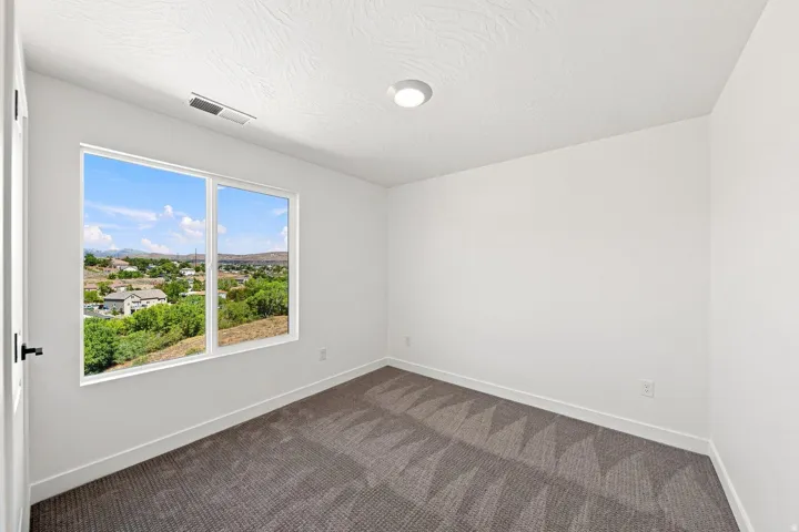 Bright room featuring a large dual-pane window, neutral textured carpet, contemporary flush-mount lighting, and white walls