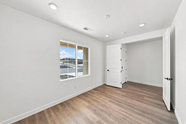 Wood-finish flooring, recessed lighting, a window with grid detailing, and a closet with bifold doors