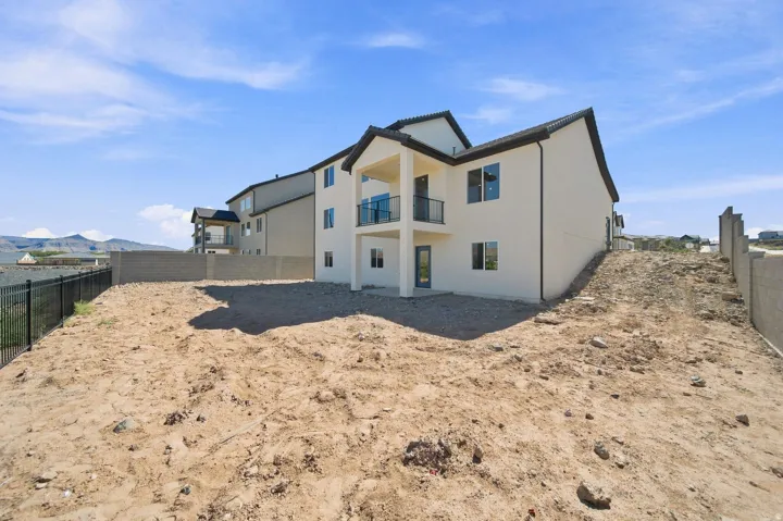 Two-story exterior with stucco finish, a second-level balcony with metal railings, and a ground-level patio door