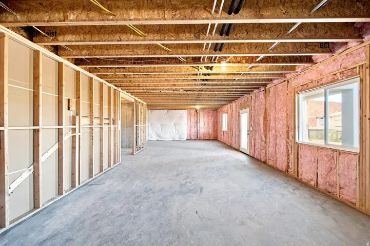 Unfinished lower level with concrete flooring, framed interior walls, insulated exterior walls, exposed ceiling joists, and multiple windows