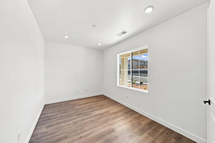 Recessed ceiling lighting, wood-finish flooring, white walls, white trim, and a white-framed window