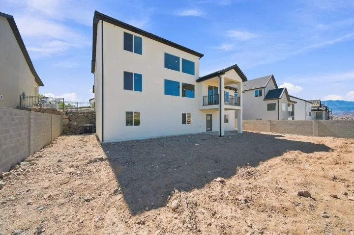 Contemporary stucco exterior with dark trim, multiple large windows, and a two-story covered balcony featuring a black railing