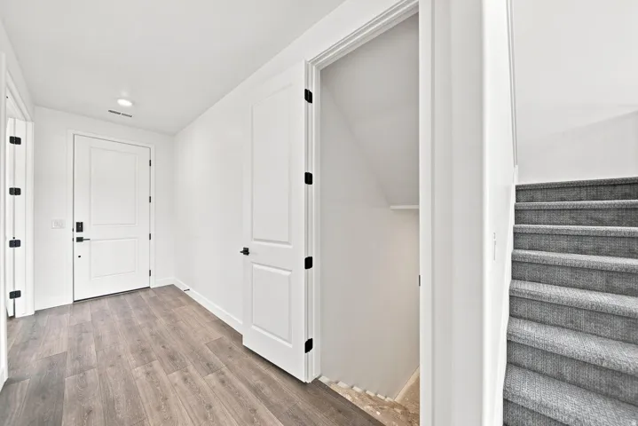 Hardwood-finish flooring, white paneled doors with matte black hardware, recessed lighting, and carpeted stairs