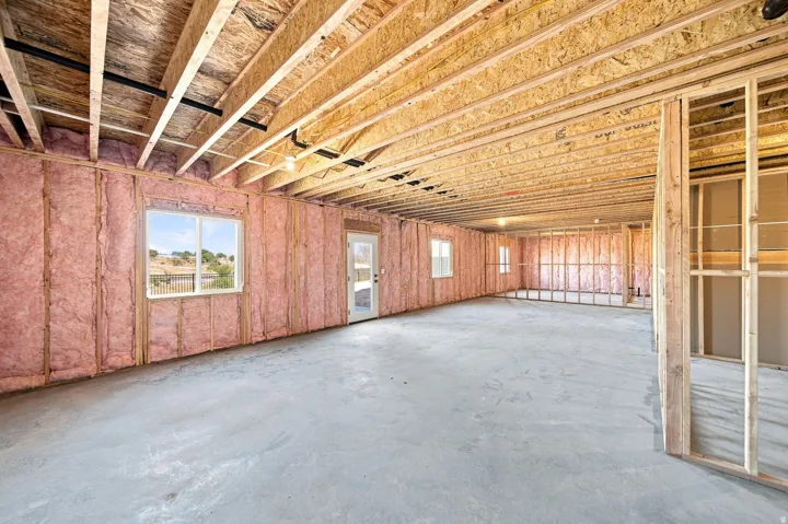 Unfinished basement with exposed ceiling joists, wood framing, insulation, concrete flooring, and multiple windows