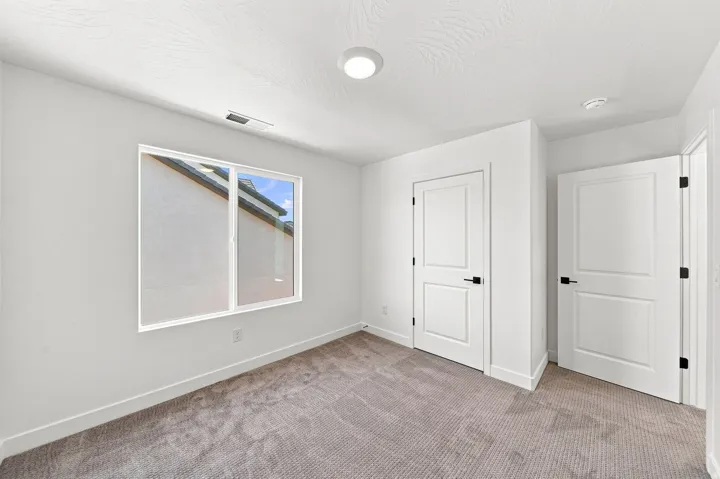 Neutral wall color, carpeted flooring, white trim, recessed lighting, and white interior doors with dark hardware