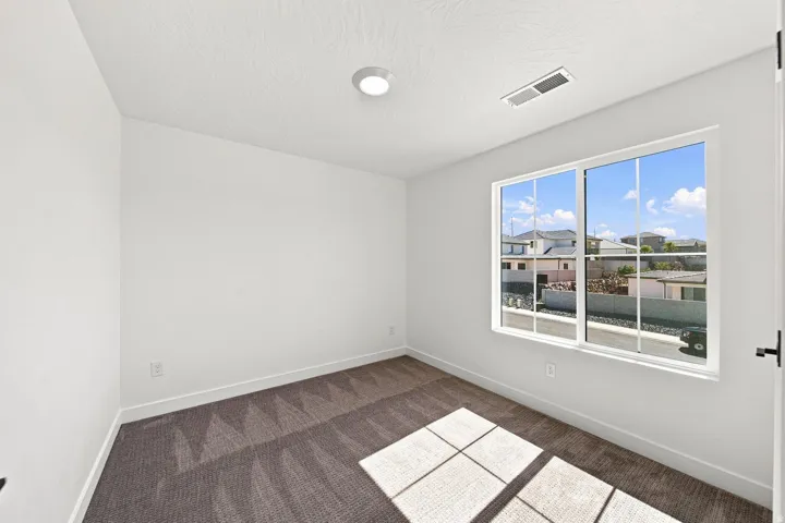 Neutral wall paint, patterned carpet flooring, recessed ceiling lighting, and a large window with white framing