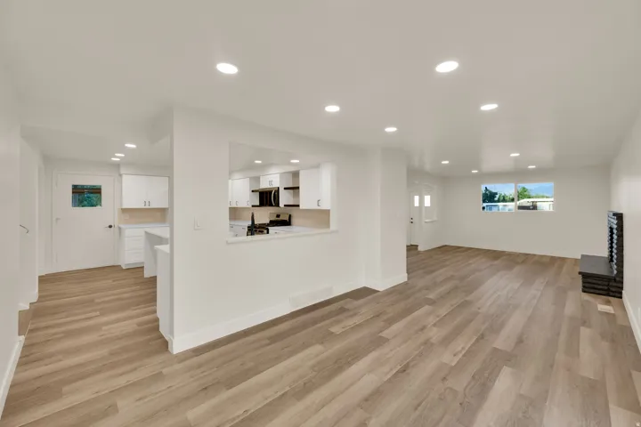 Open-concept living area with wood-finish flooring, recessed lighting, and white walls