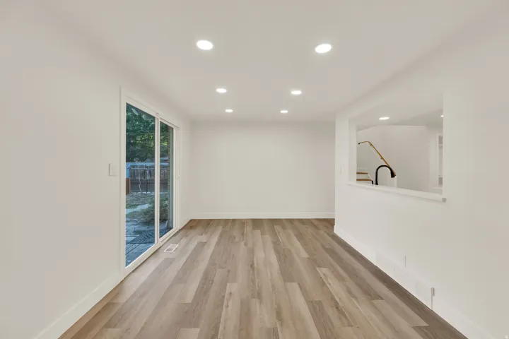 Wood-finish flooring, recessed lighting, white walls, and a sliding glass door to the exterior