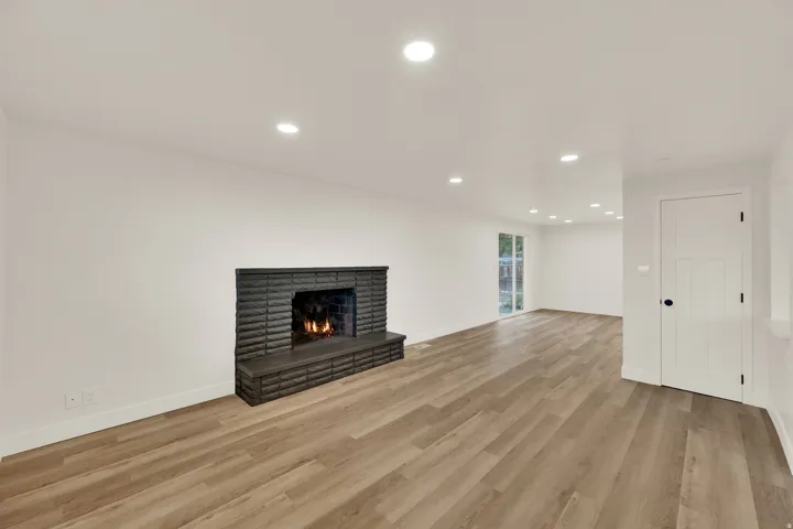 Wood-finish flooring, recessed lighting, and a dark brick fireplace with a hearth