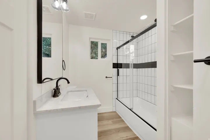White vanity with a light-toned countertop, rectangular undermount sink, and dark-toned faucet