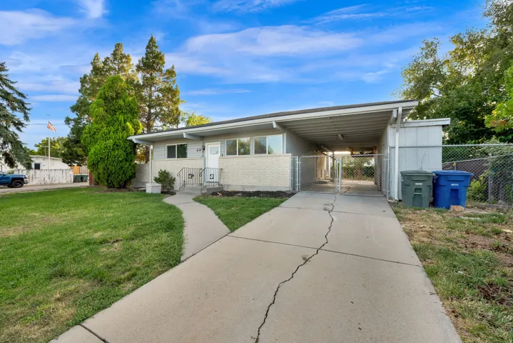 Ranch-style exterior with a brick and siding facade, a paved driveway, a covered carport, and a front walkway