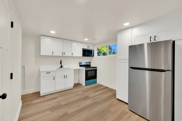 Kitchenette featuring white cabinetry, stainless steel appliances, light-toned wood-finish flooring, and recessed lighting