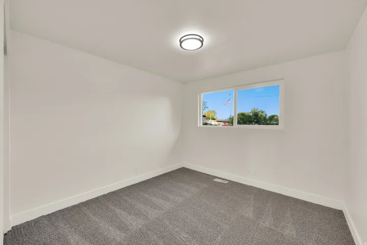 Neutral wall paint with carpeted flooring and a flush-mount ceiling light