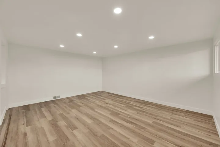 Recessed ceiling lighting, light wood-finish flooring, white walls, and window