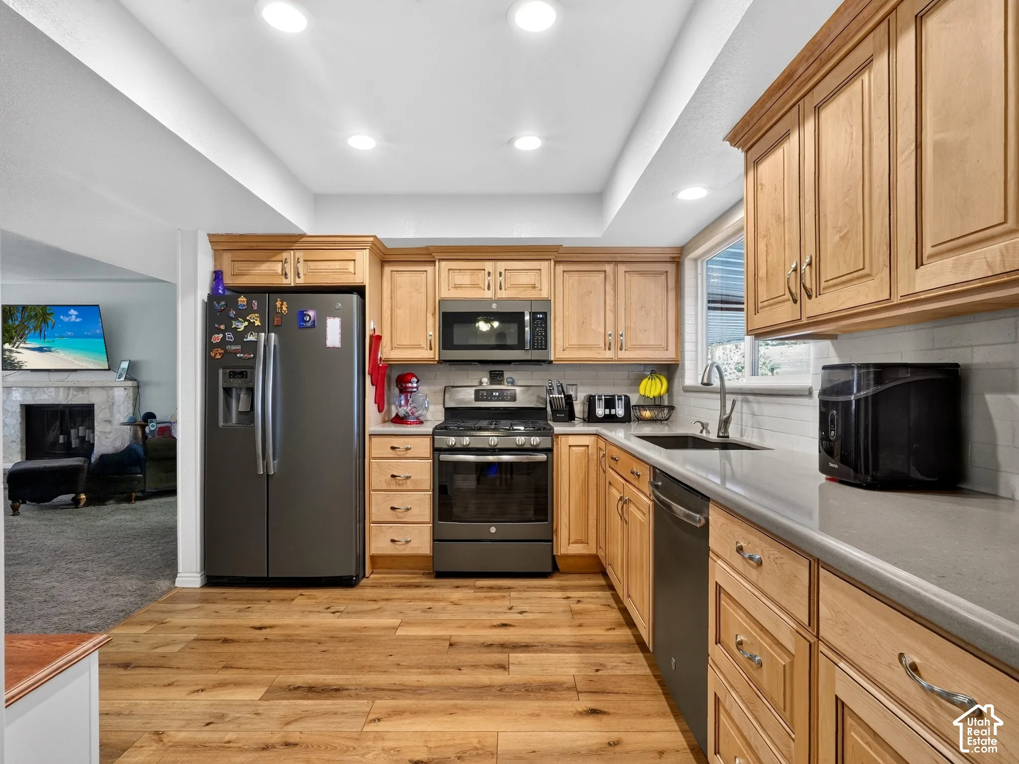Kitchen featuring wood-finish flooring, recessed lighting, wood cabinetry, a tile backsplash, and dark gray appliances