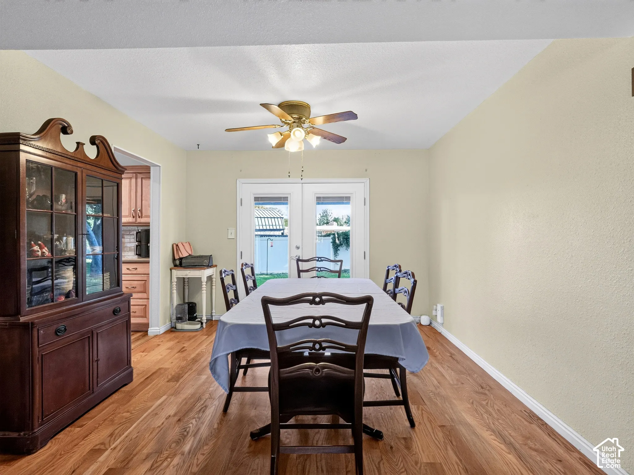 Wood-finish flooring throughout, ceiling fan with integrated lighting, and double glass-panel doors
