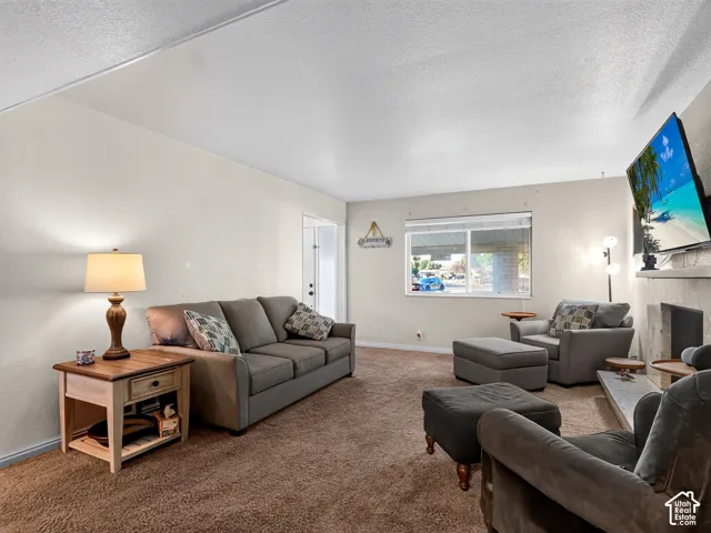 Carpeted living area with light-toned walls, a large window, and a built-in fireplace