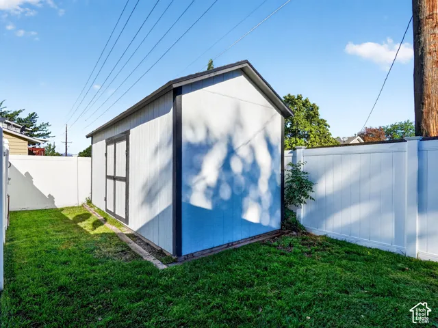 Storage shed with double doors, pitched roof, and surrounding privacy fencing