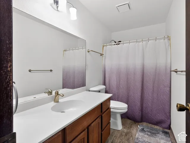 Wood-finish flooring with a white vanity featuring a single-basin sink, brushed nickel faucet, and integrated countertop