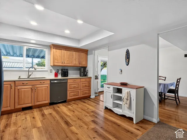 Kitchen featuring wood-finish flooring, recessed lighting, wood cabinetry, a tile backsplash, and a stainless steel sink