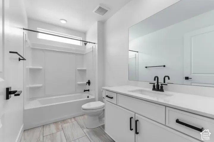 Bathroom featuring a single vanity with stone-finish countertop, undermount sink, and black fixtures