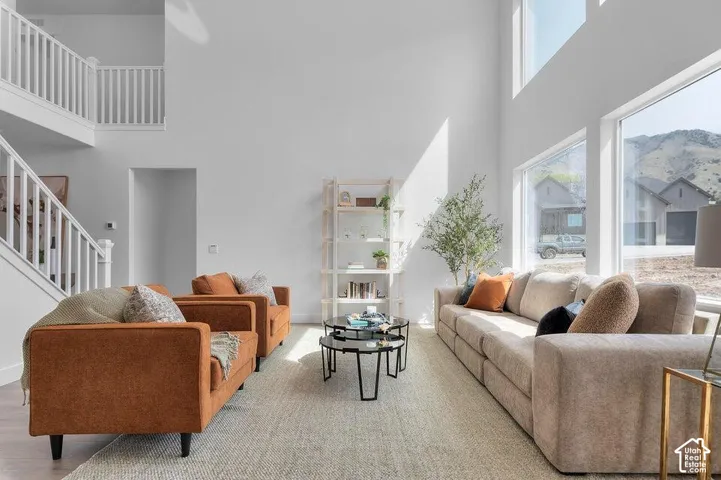 Two-story living area with high ceilings, expansive windows, and a white spindle staircase