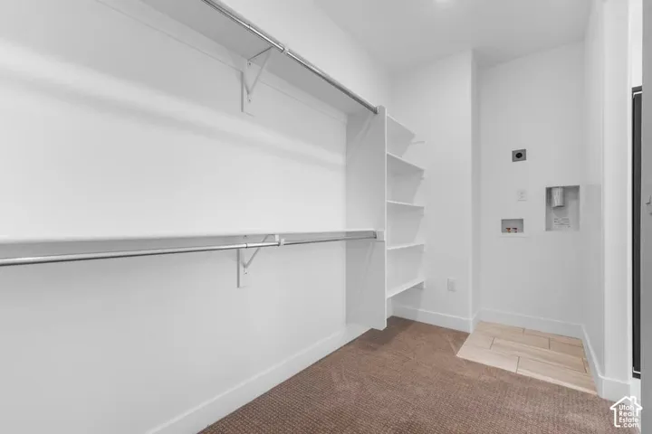 Built-in shelving, dual hanging rods, carpet flooring, tile flooring, and laundry hookups