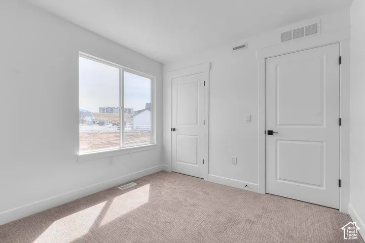 Neutral-toned carpet flooring, white walls, and a large window with white trim