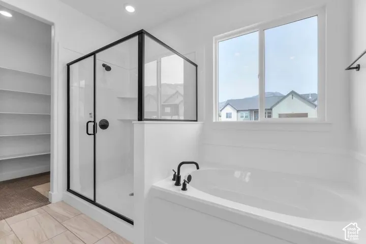 Soaking tub with matte black fixtures, separate shower enclosure with black framing, and a built-in shelving unit