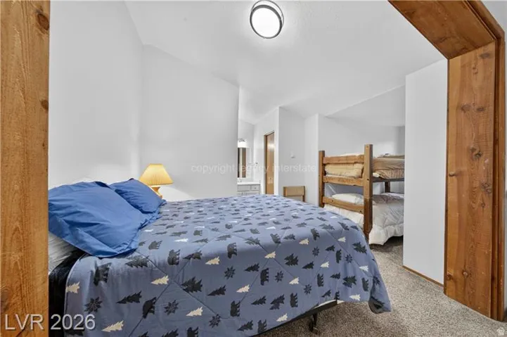 Bedroom featuring an arched wood-paneled doorway, carpet flooring, a flush-mount ceiling light, and white painted walls