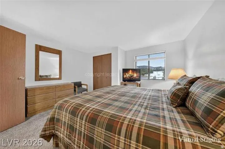 White walls with a single window, two wood-finish doors, and soft carpet flooring
