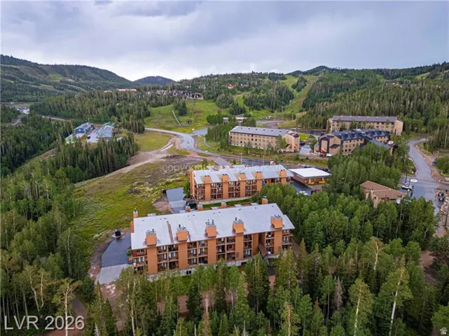 Mountainous terrain with dense evergreen forests surrounding multiple multi-story buildings featuring balconies