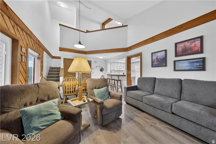 Vaulted ceiling with exposed wood beams, wood-finish flooring, and a second-story balcony overlook