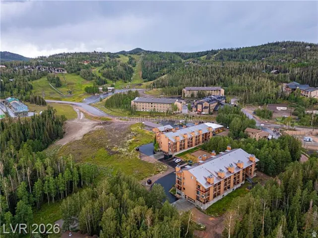 Terraced residential structures with multiple balconies and pitched roofs nestled within a wooded mountainous landscape