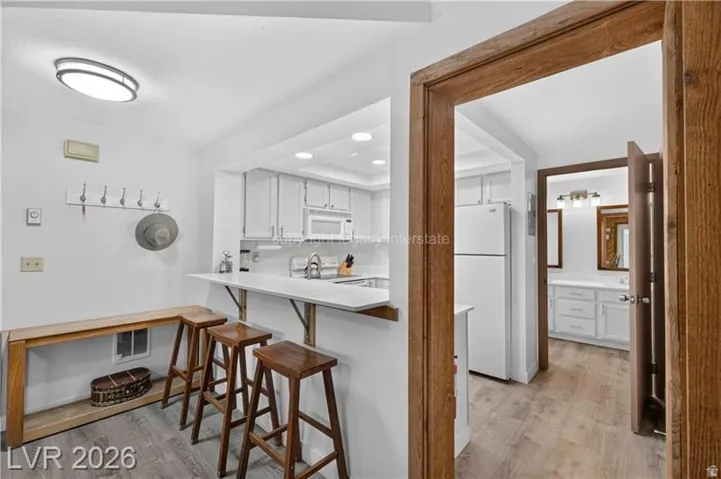 Kitchen pass-through with a breakfast bar, white cabinetry, and recessed lighting