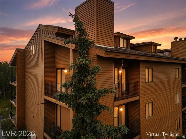 Multi-level building with horizontal wood siding, multiple private balconies with black metal railings, and dormer windows
