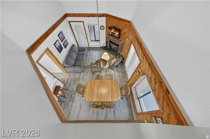 Efficient floor plan showcasing wood-finish flooring throughout, abundant natural light from multiple windows, wood-trimmed walls, a dining area with wood table, and built-in kitchen cabinetry with appliances