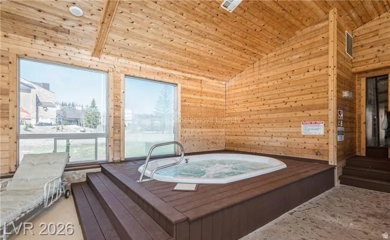 Indoor spa with integrated steps, natural wood-paneled walls, vaulted wood-plank ceiling, and large windows